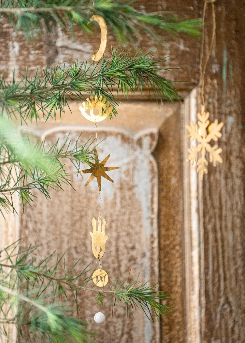 Decorative gold ornaments hanging from a Christmas tree with a rustic wooden background.