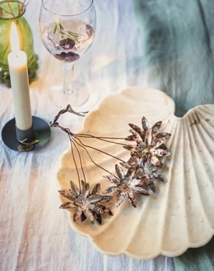 Decorative pumpkin with star-shaped decorations on a table with a candle and glass.