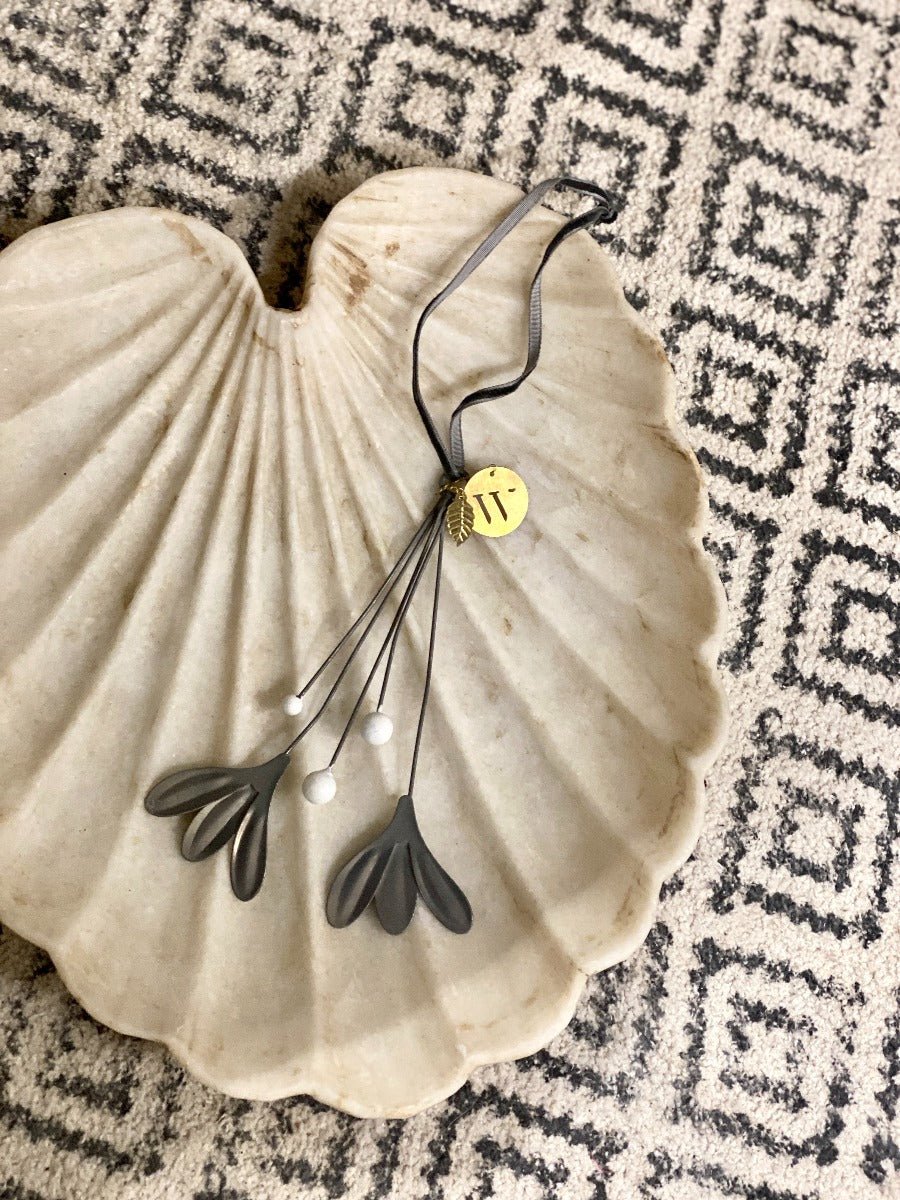Decorative necklace with a gold tag on a shell against a patterned background