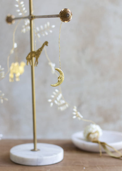 Gold crescent moon ornament on a stand with a marble base against a neutral background