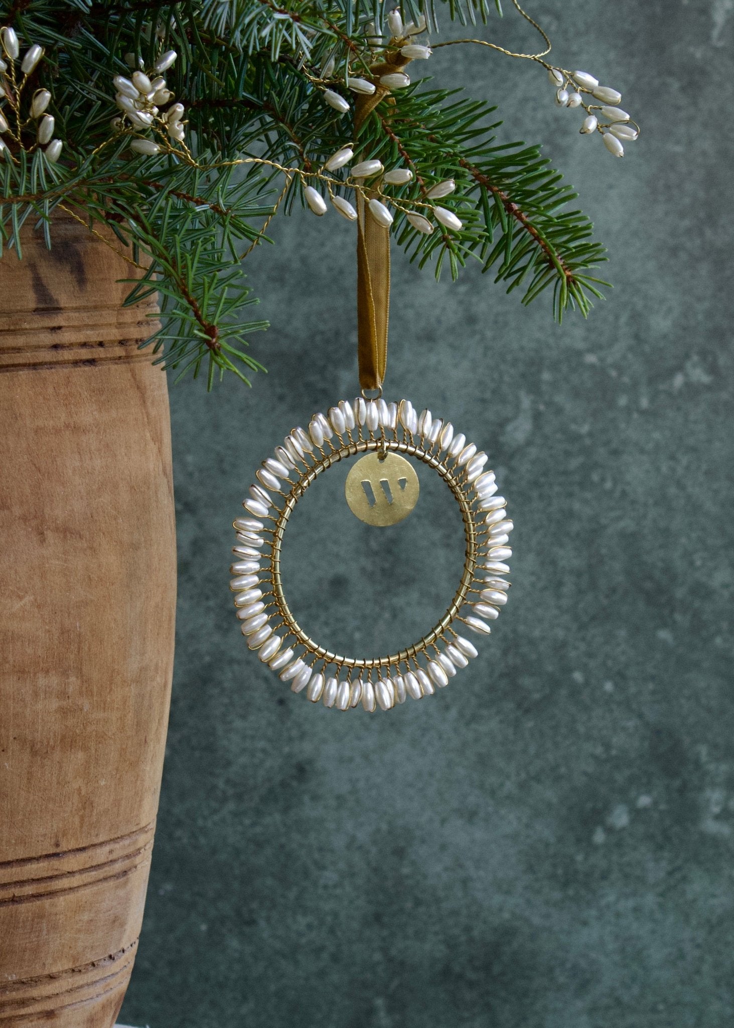 Decorative ornament with beads hanging from a branch against a textured green background