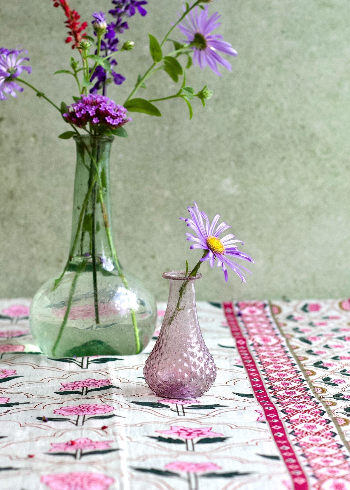 Clear glass vase with flowers on a patterned tablecloth