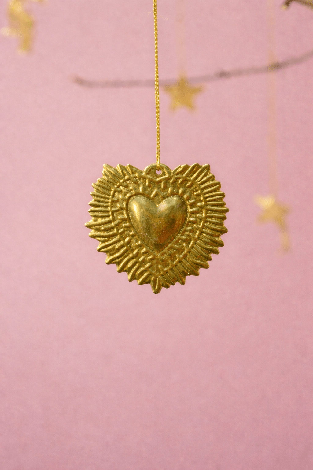 Gold heart-shaped pendant with star details on a pink background
