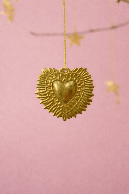 Gold heart-shaped pendant with star details on a pink background