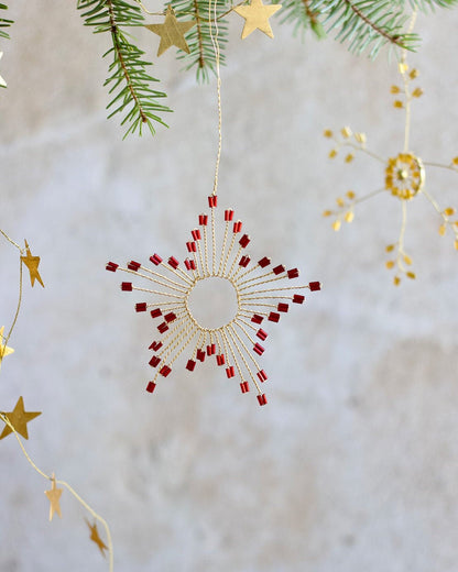 Decorative Christmas ornament with red and gold stars on a textured white background