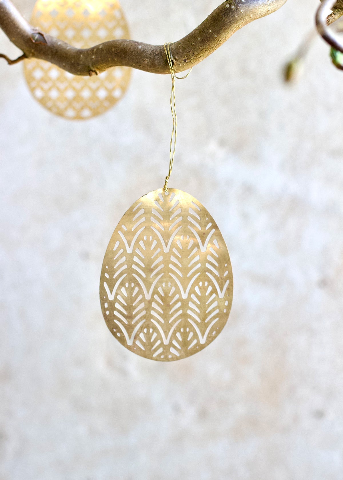 Gold earring with intricate pattern hanging from a branch