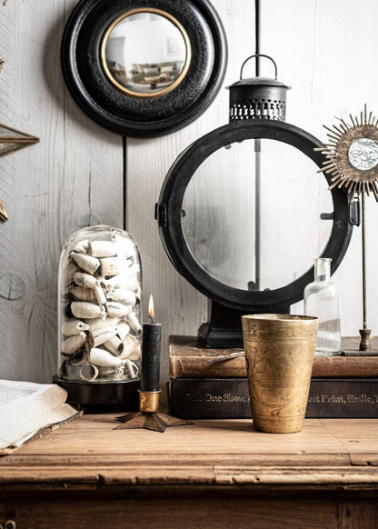 A table featuring a vase, a lit candle, and a decorative mirror reflecting the surrounding space.
