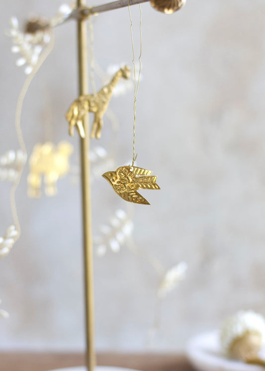 Gold bird ornament hanging from a string with blurred lights in the background
