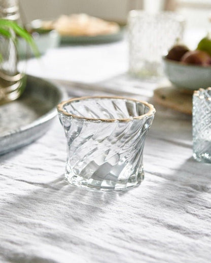 Clear glass votive holders on a marble table with a blurred background