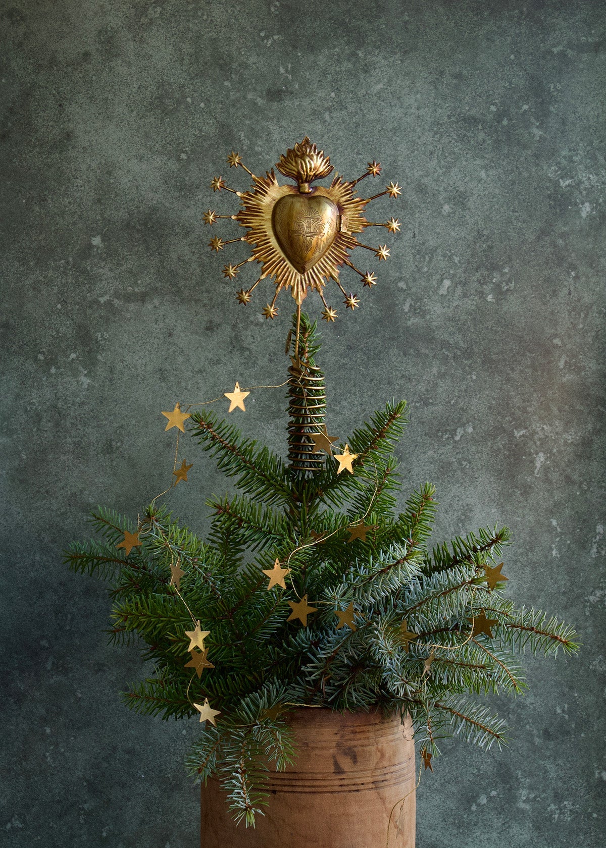 Decorative Christmas tree with gold star decorations and a heart-shaped gold ornament against a dark background.