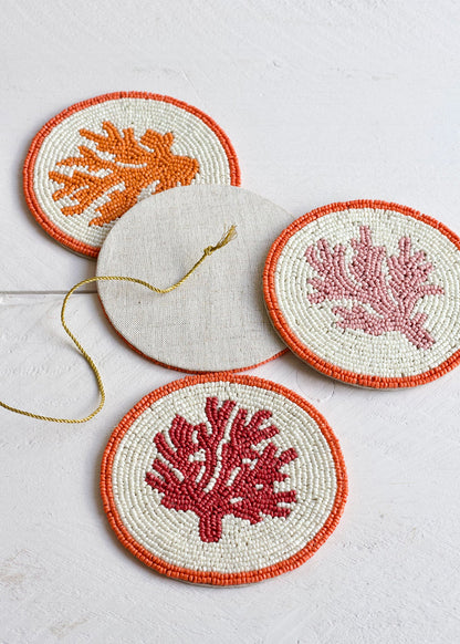 Set of three embroidered coasters with coral designs on a light background