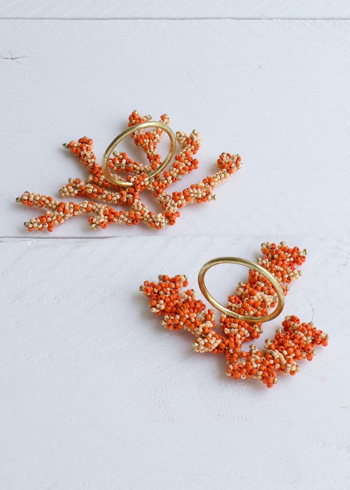 Pair of orange and gold earrings on a light gray background