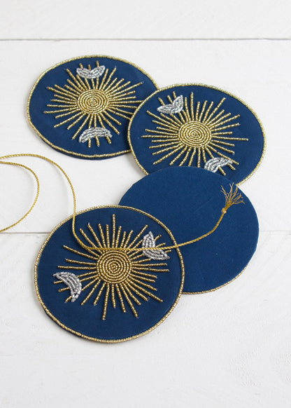Set of four blue coasters with gold and white designs on a white surface