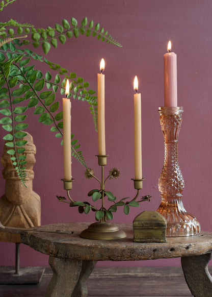 Decorative candle holder with lit candles on a rustic table against a purple wall.