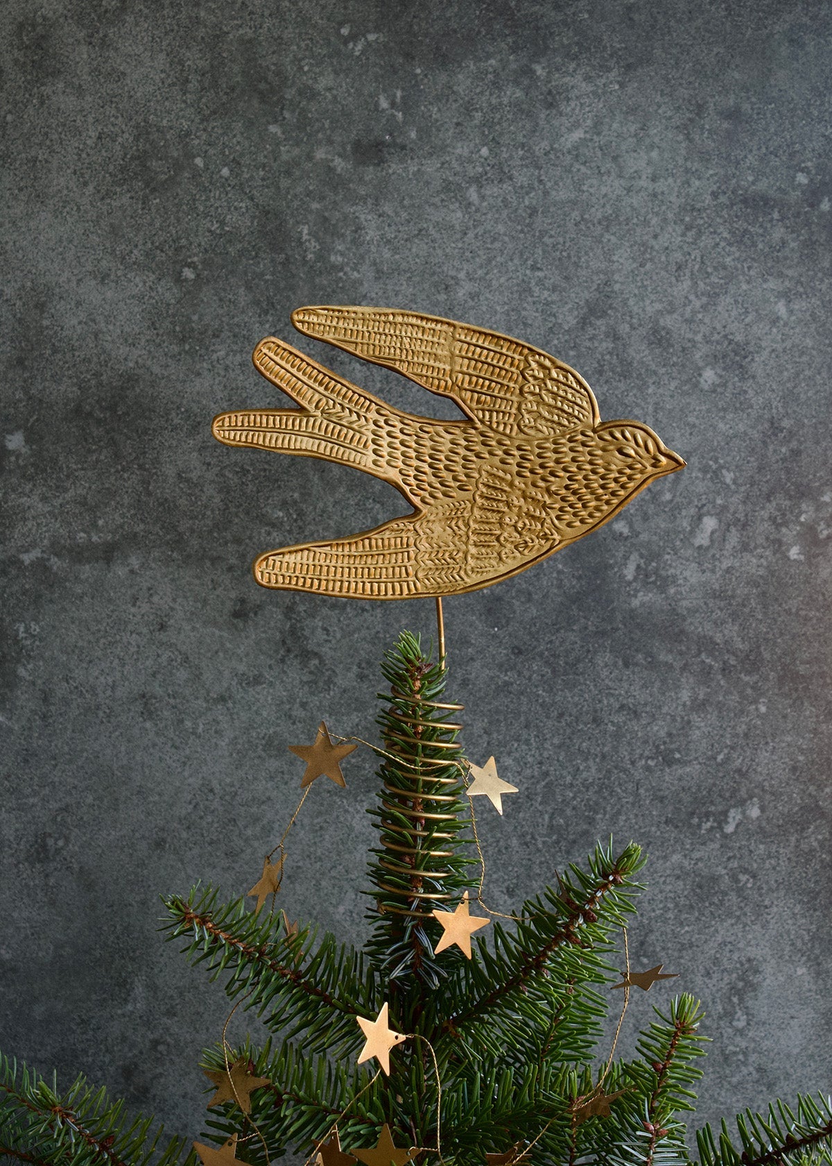 Gold bird ornament on a Christmas tree with a gray background