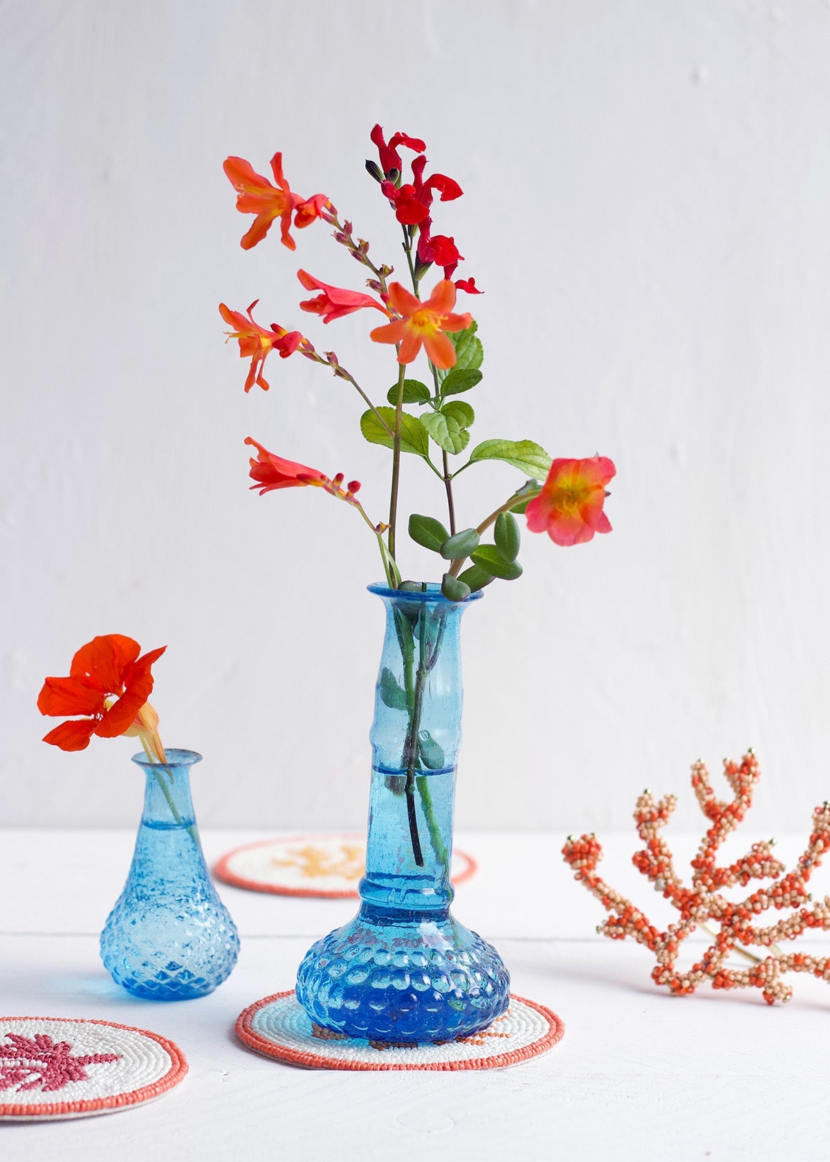Blue textured vase with red flowers on a white background