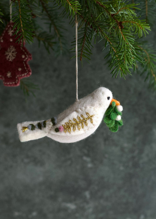 Decorative bird ornament with gold accents and a green branch, hanging from a tree.